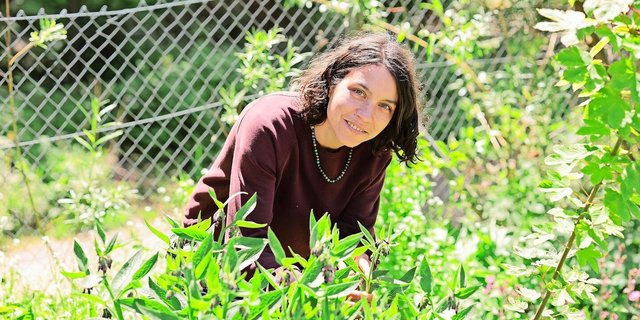 Nina Shereida hinter einem Echten Beinwell, einer Arznei- und Heilpflanze, die unter anderem bei Gelenkbeschwerden, Prellungen und Zerrungen eingesetzt werden kann.