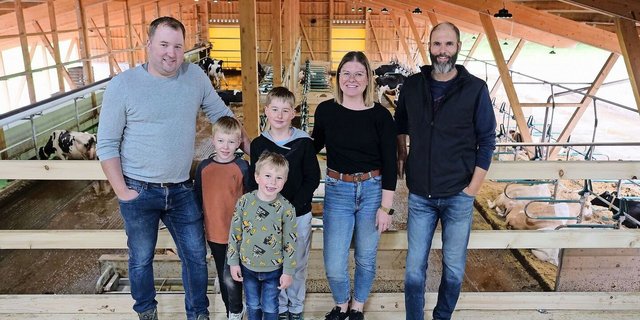 Martin und Andrea Blaser mit ihren Kindern Niklas, Magnus und Linus sowie Markus Schafroth (v. l. n. r.) in ihrem neu gebauten Stall. Ganz links ist das obenliegende Futterband zu sehen.
