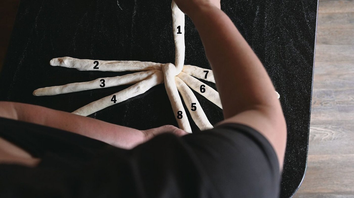 Die linke Hand legt den Strang neben Strang 5, die rechte behält Strang 1 in der Hand. 