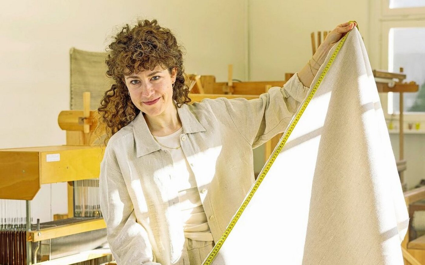 Mira Durrer mit einem ihrer Stoffe in ihrem Atelier in Luzern: Im Hintergrund die Handwebstühle. Bei der 34-Jährigen kann man Leinen aus der Schweiz in kleinen Mengen bestellen. 
