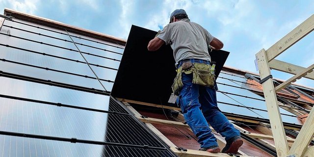 Montage von PV-Modulen für eine Indachanlage auf einem Neubau. Solche Systeme sind zwar teurer als Aufdachanlagen, dafür können die Ziegel eingespart werden.