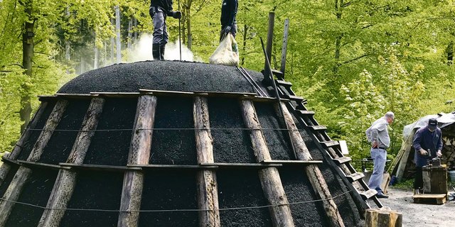 Einige Tage später qualmt der Kohlenmeiler und benötigt alle drei bis vier Stunden Pflege: Über Zuglöcher regulieren die Köhler die Luftzufuhr und damit den Verkohlungsprozess.