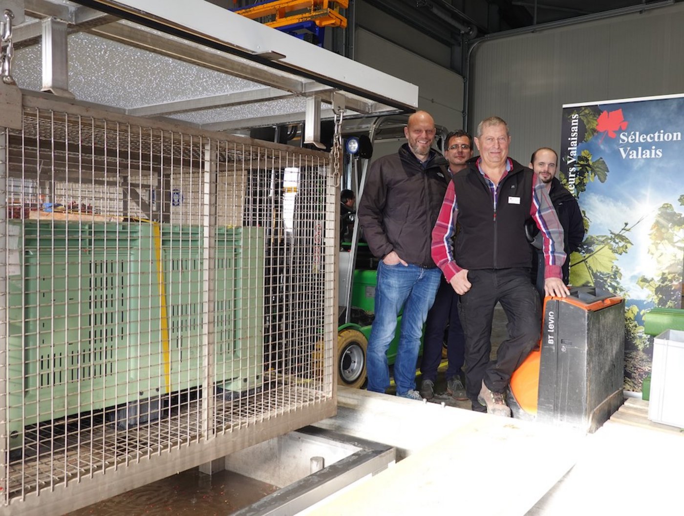 Posieren mit der Heisswasserbehandlungsmaschine: (v.l.) Pierre-André Roduit, Chef des Weinbauamts, Thierry Castellazzi, Bundesamt für Landwirtschaft, Paul-Maurice Burrin, Präsident der «Société des pépinéristes viticulteurs», Laurent Maret, Chef des Amts für Strukturverbesserungen. (Bild zVg)