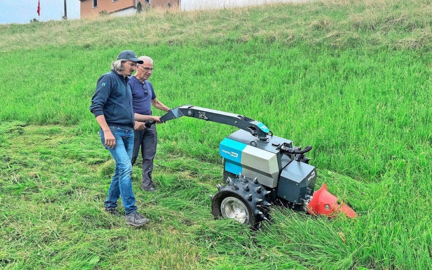 Gian Caduff (mit Mütze) von Novaziun erklärt einem Teilnehmer die Bedienung des elektrisch angetriebenen Monotrac. 