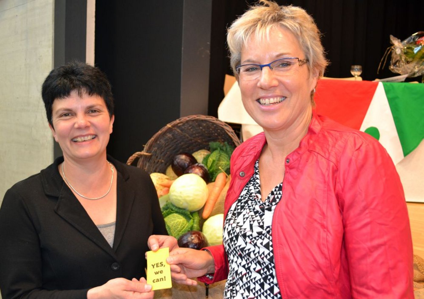 Yes, we can! Die abtretende Präsidentin Christine Gerber (links) übergibt ihrer Nachfolgerin Rita Gfeller in der Mehrzweckhalle in Ins ihr Glücksbringer-Nastüechli, das sie 2008 bei ihrem Amtsantritt erhielt.  (Bild Alois Heinzer)