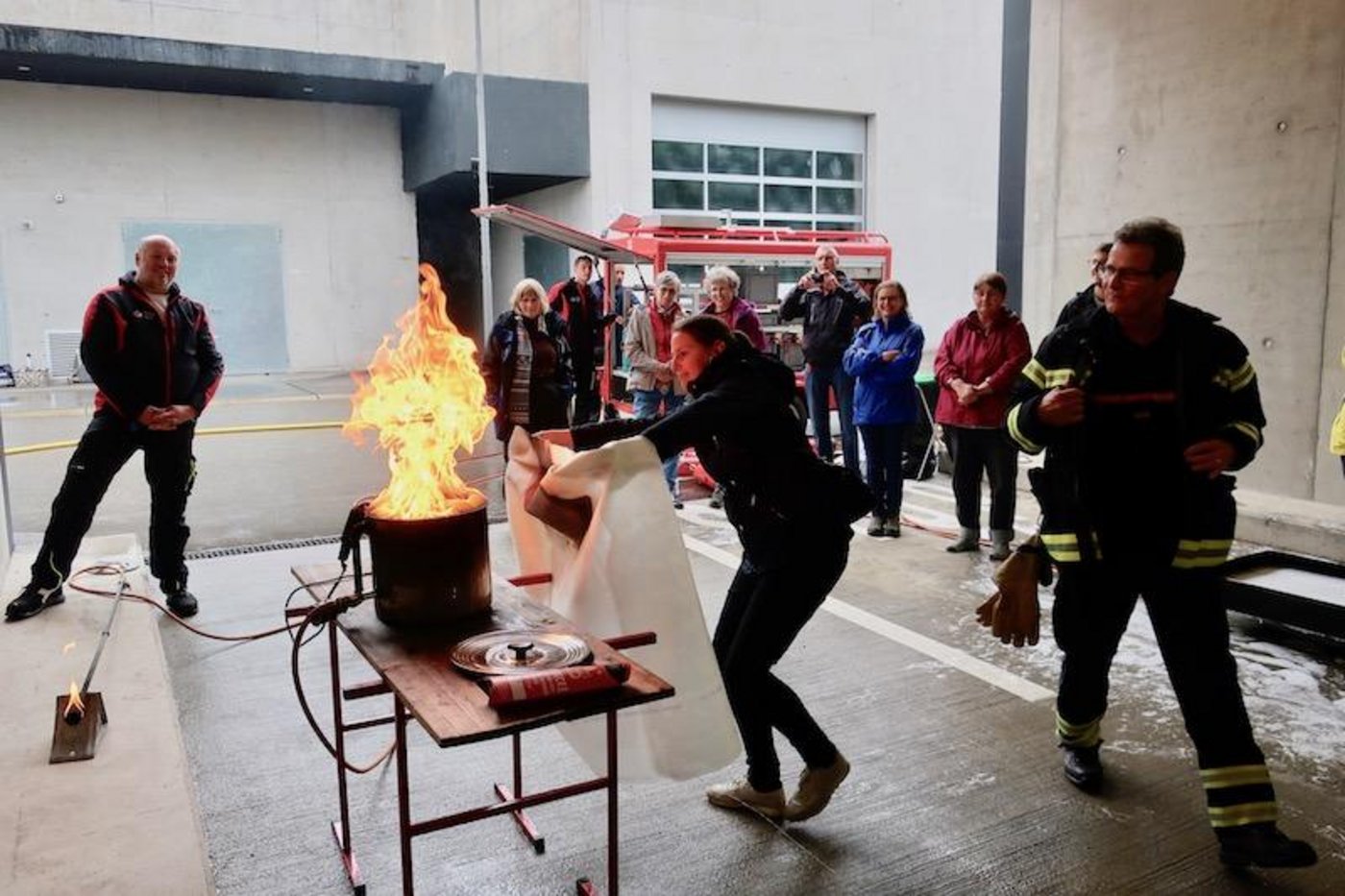 Eine Gruppe Bäuerinnen übt das Löschen eines Fritteusenbrands mit der Löschdecke: Die Decke darf nicht von oben über die Fritteuse gestülpt werden, sondern muss über den Fritteusenrand geschoben werden. (Bilder und Video Esther Thalmann)