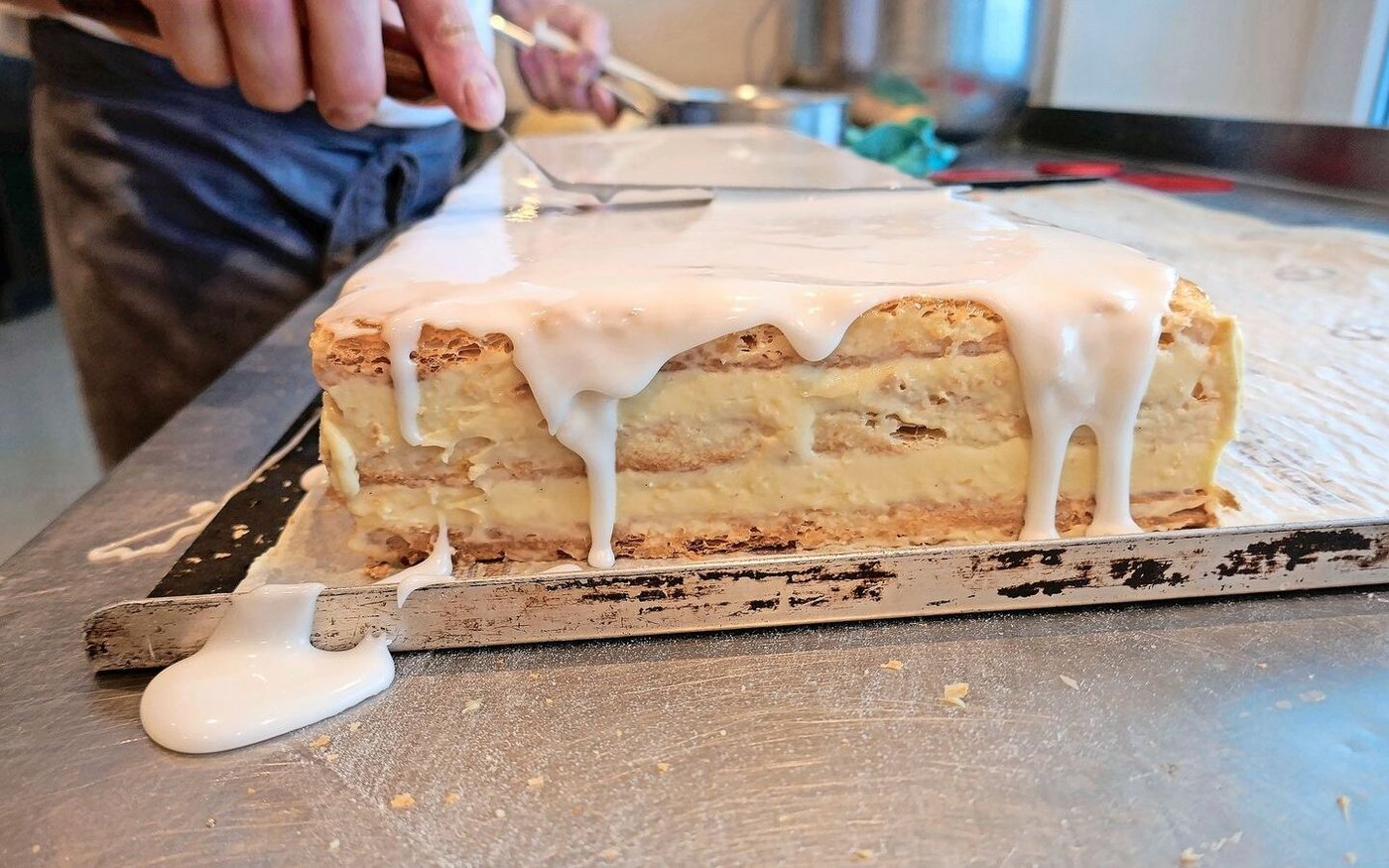 Das Auftragen der obersten Schicht, des Fondants. Es braucht auch hier Sorgfalt, damit keine «Teigbrösmeli» die glatte Glasur zerstören.