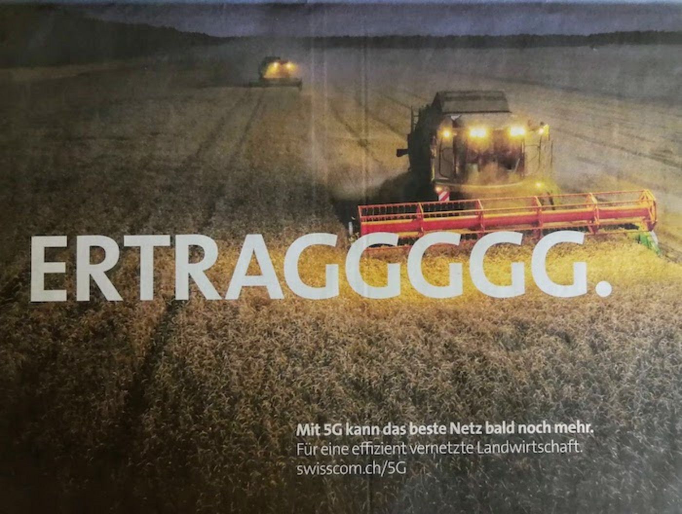 Zwei Mähdrescher mit Beleuchtung dreschen in dunkler Nacht Weizen. Mit diesem Sujet wirbt der grösste nationale Mobilfunkanbieter für eine effizient vernetzte Landwirtschaft und für die neue 5G-Technologie in der Zeitung Der Bund. (Bild sbu)