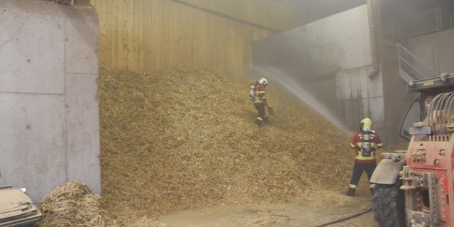 Feuerwehrleute bekämpfen den Mottbrand im Holzschnitzellager. (Bilder Kapo GR)