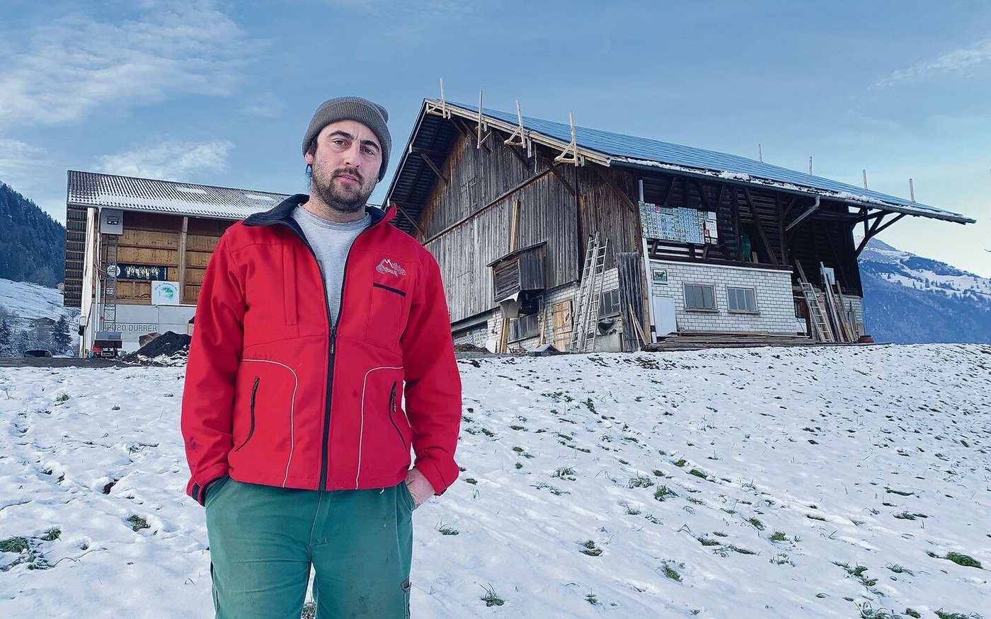 Michael Durrer vor den Gebäuden auf Heubüeli. Der alte Stall wurde bereits mit PV-Modulen belegt (r.). Bald werden solche mit viel Eigenleistung auch auf dem Dach und der Fassade der neuen Scheune montiert. 