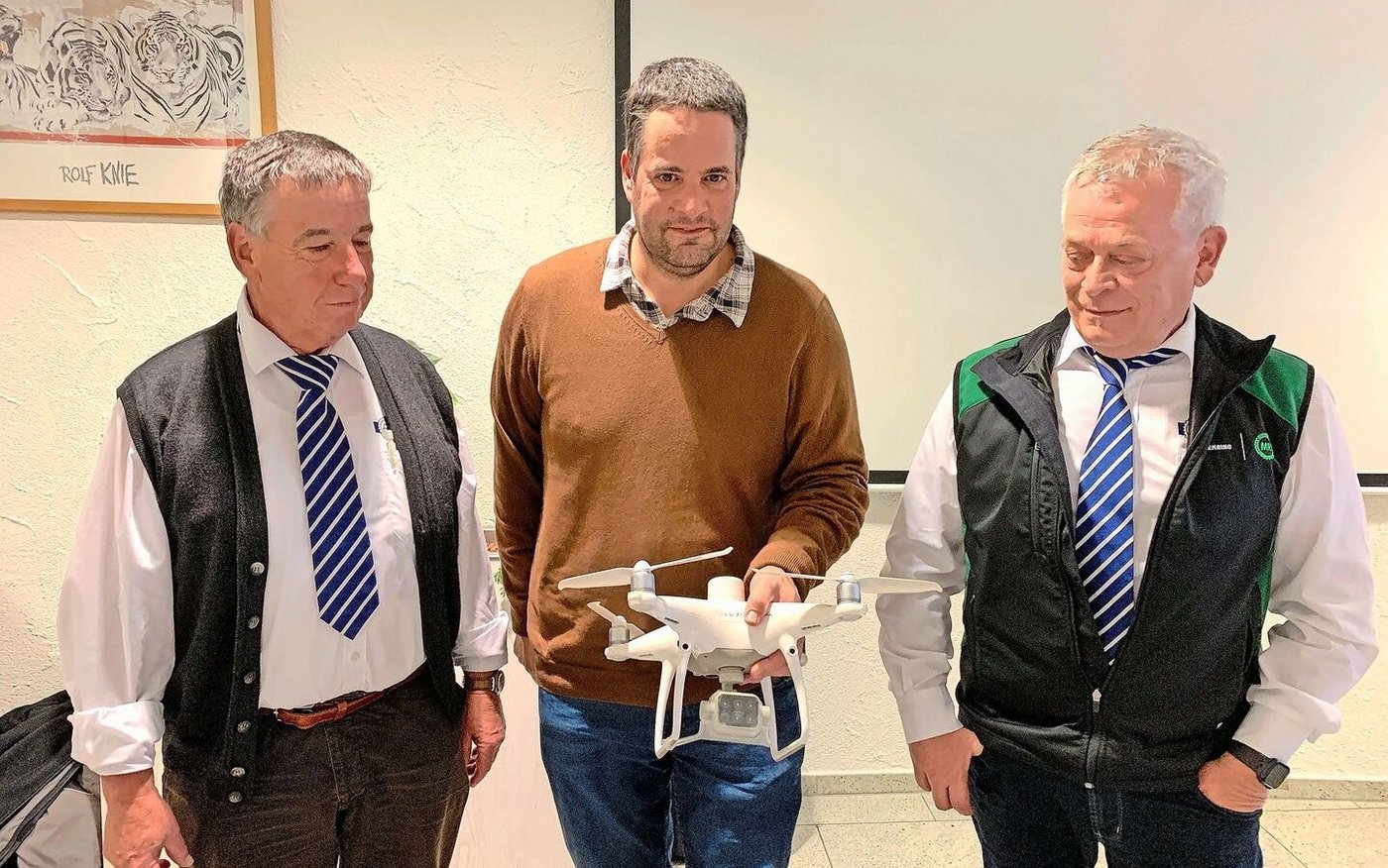 Präsident Toni Moser (l.) und Geschäftsführer Sepp Erni (r.) lassen sich von Marco Landis eine Drohne mit Wärmebildkamera für den Einsatz in der Landwirtschaft erklären.  