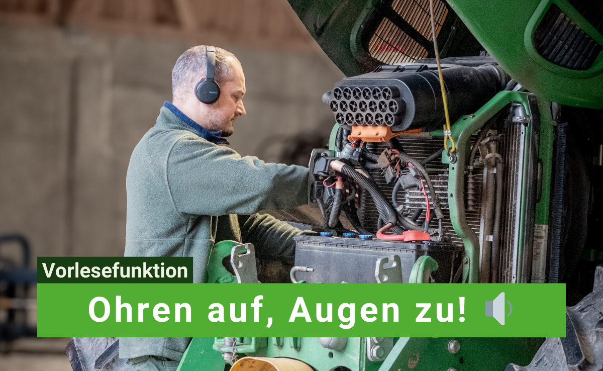 Mann arbeitet am Traktor mit Kopfhörer an